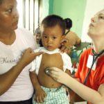 Medical student Katie Fratino uses a stethoscope to examine a young boy.