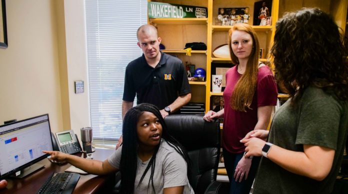 Mercer professor Dr. Lane Wakefield (standing, left) and students Marissa James (sitting), Kendra Houghton (center) and Emily Stepp talk about the Google advertising campaign project.