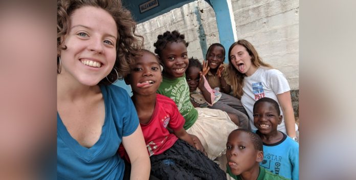 Sarah Harris, left, and Carrie Bezanson, right, are shown with orphans at Home of Hope in Guinea during their internship in spring 2019.