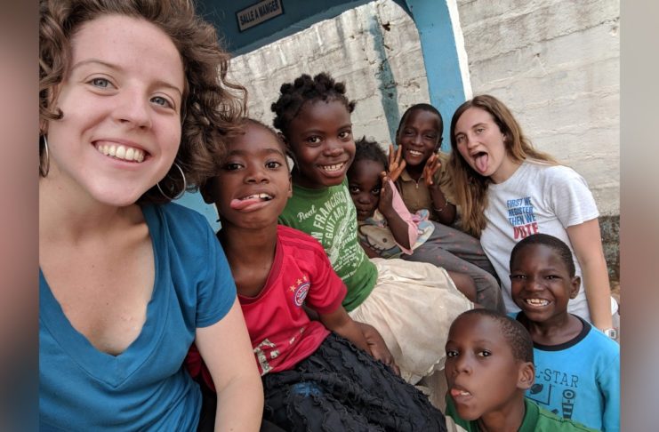 Sarah Harris, left, and Carrie Bezanson, right, are shown with orphans at Home of Hope in Guinea during their internship in spring 2019.
