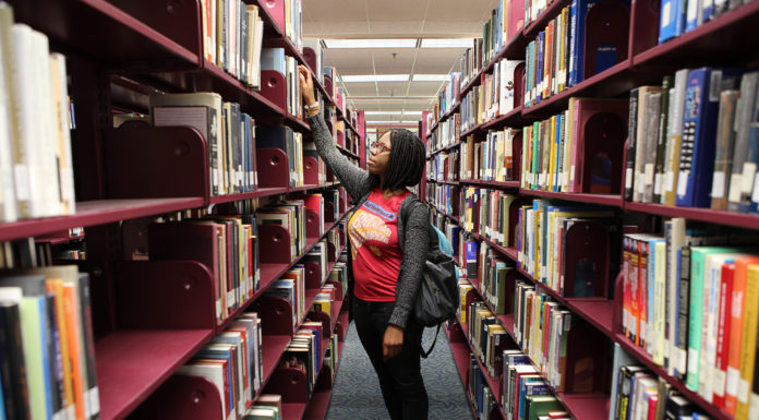 Virtual Book Club connects Mercer book lovers A woman pulls a book off a shelf in a library