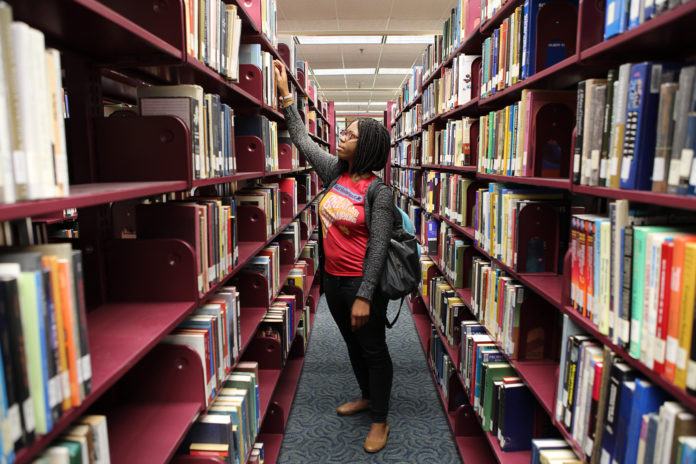 A woman pulls a book off a shelf in a library