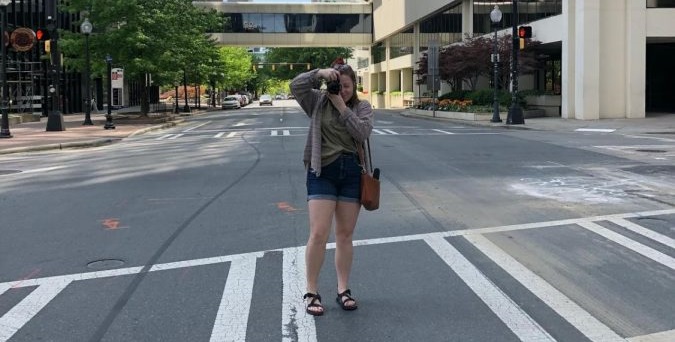 Reilly Moncrief stands in a crosswalk holding her camera to her face
