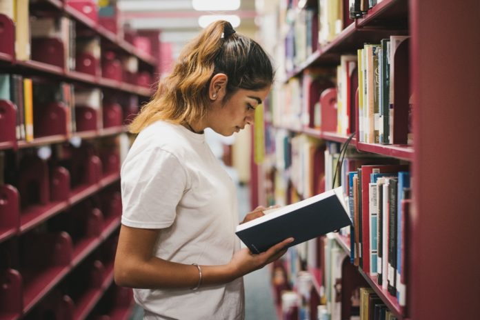 Woman looking at book in library