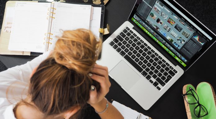 How to stay focused when you’re overwhelmed | Ask Kelly Women holding her head in her hands and looking stressed at a computer