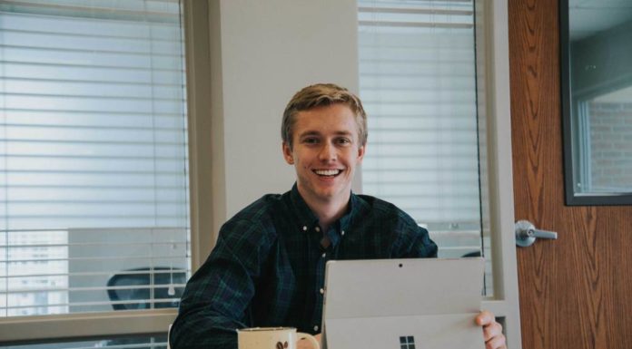 How a Mercer On Mission trip led to a start-up coffee business Shane Buerster sits at computer next to Z Beans Coffee mug