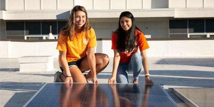 Two students hold a solar panel