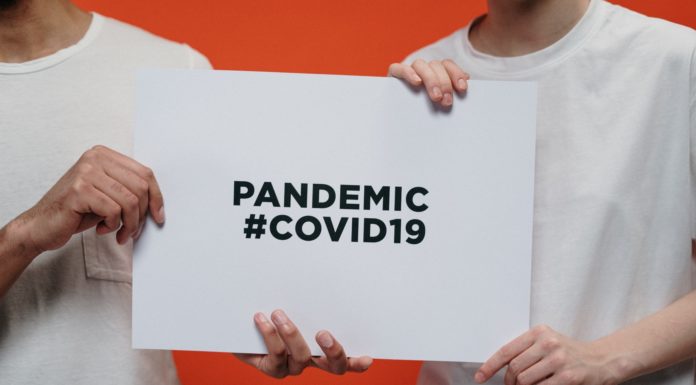 What’s the impact of COVID-19 on local businesses? People holding white paper with pandemic #covid19 text