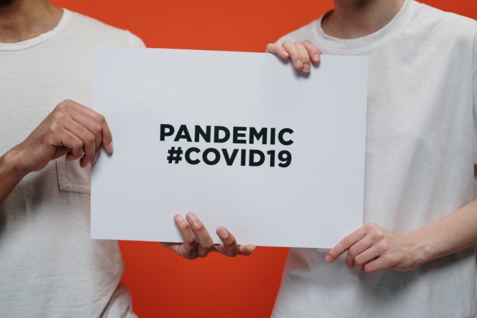People holding white paper with pandemic #covid19 text