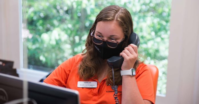 Student talks on telephone while wearing a mask