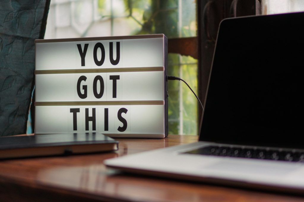 Black and white laptop in front of sign that says, "You got this."
