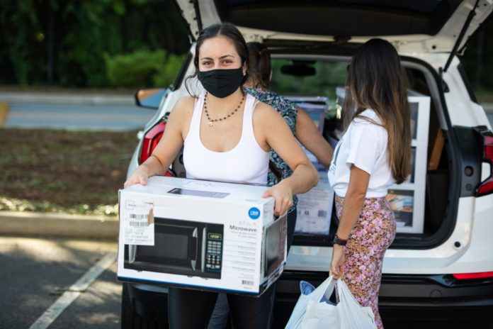 A young woman carries a microwave in a box