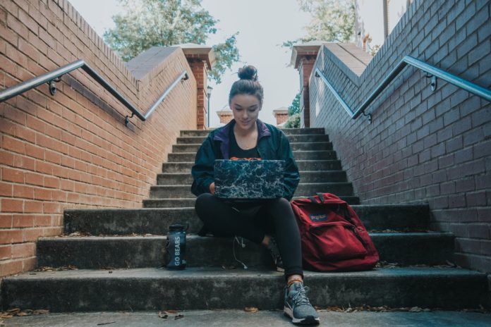 Student sitting on steps looking at laptop