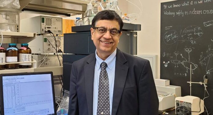 Professor receives grant to help fight effects of some chemical warfare Dr. Ajay Banga stands next to a computer in his lab; a chalkboard with writing on it is behind him.