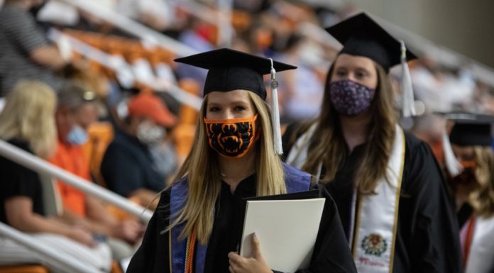 Don’t pass up a chance for success to avoid failing | Ask Kelly Two women wearing masks and caps and gowns walk at commencement.