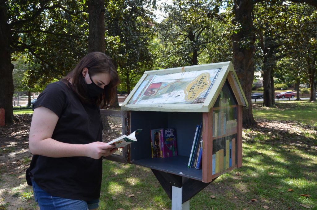 Malia Ayers, a sophomore education major, checks the inventory at the Little Free Library near the playground at Tattnall Square Park.