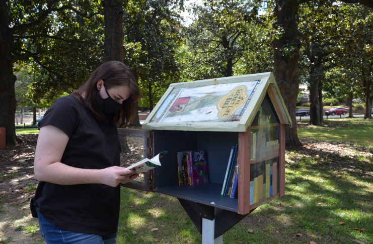 Malia Ayers, a sophomore education major, checks the inventory at the Little Free Library near the playground at Tattnall Square Park.
