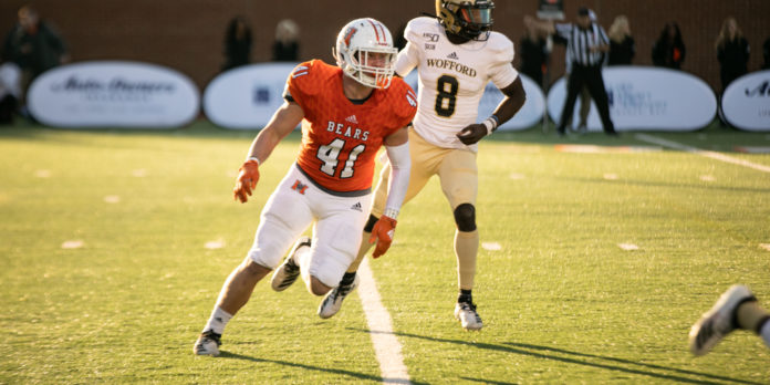 Number 41, wearing an orange Mercer Bears jersey, runs on the football field