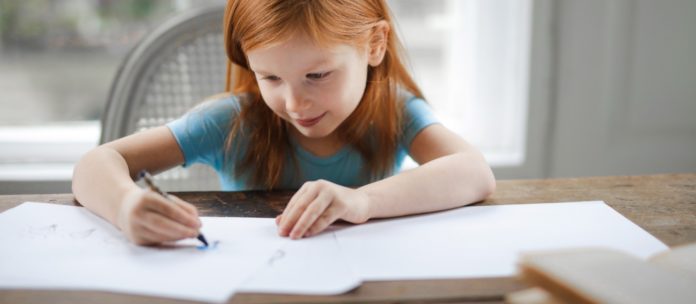child writing on paper at table