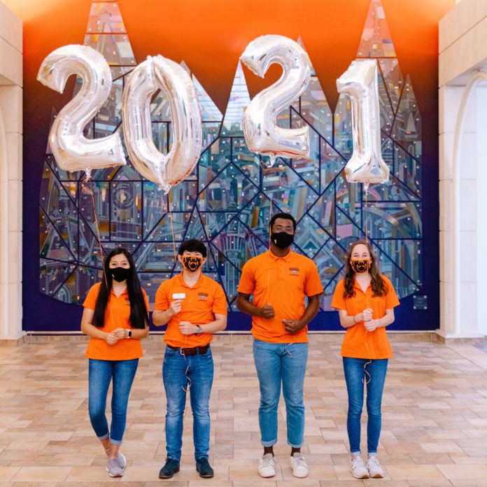 Students wearing orange shirts hold 2021 balloons