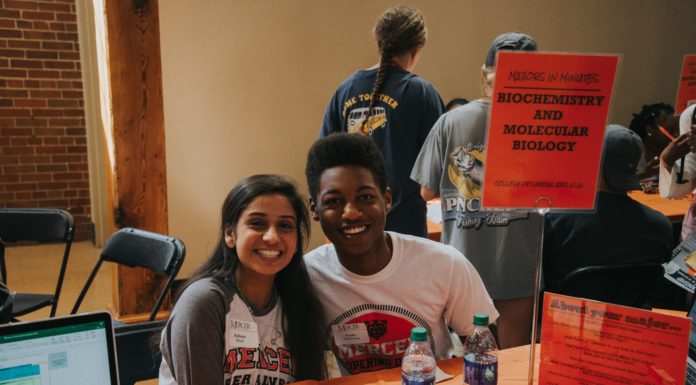 How do I choose a major? | Ask Kelly Two students sit next two a sign that says "Biochemistry and Molecular Biology"