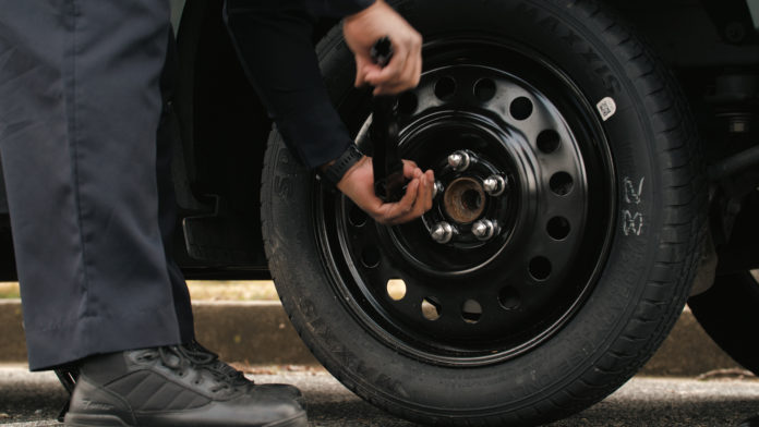 a man uses a lug wrench on a spare tire