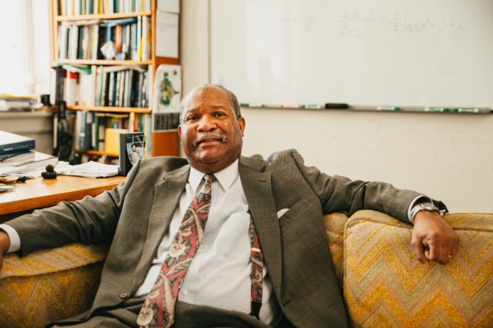 Dr. Kedrick Hartfield sits on a couch in his office