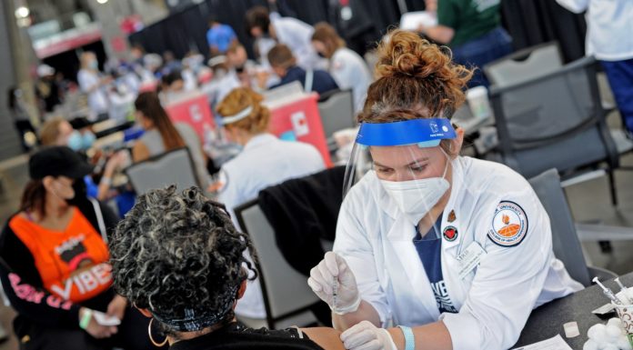 Physician assistant students give thousands of COVID-19 vaccines in Atlanta A woman in a lab coat gives a woman with gray hair a shot