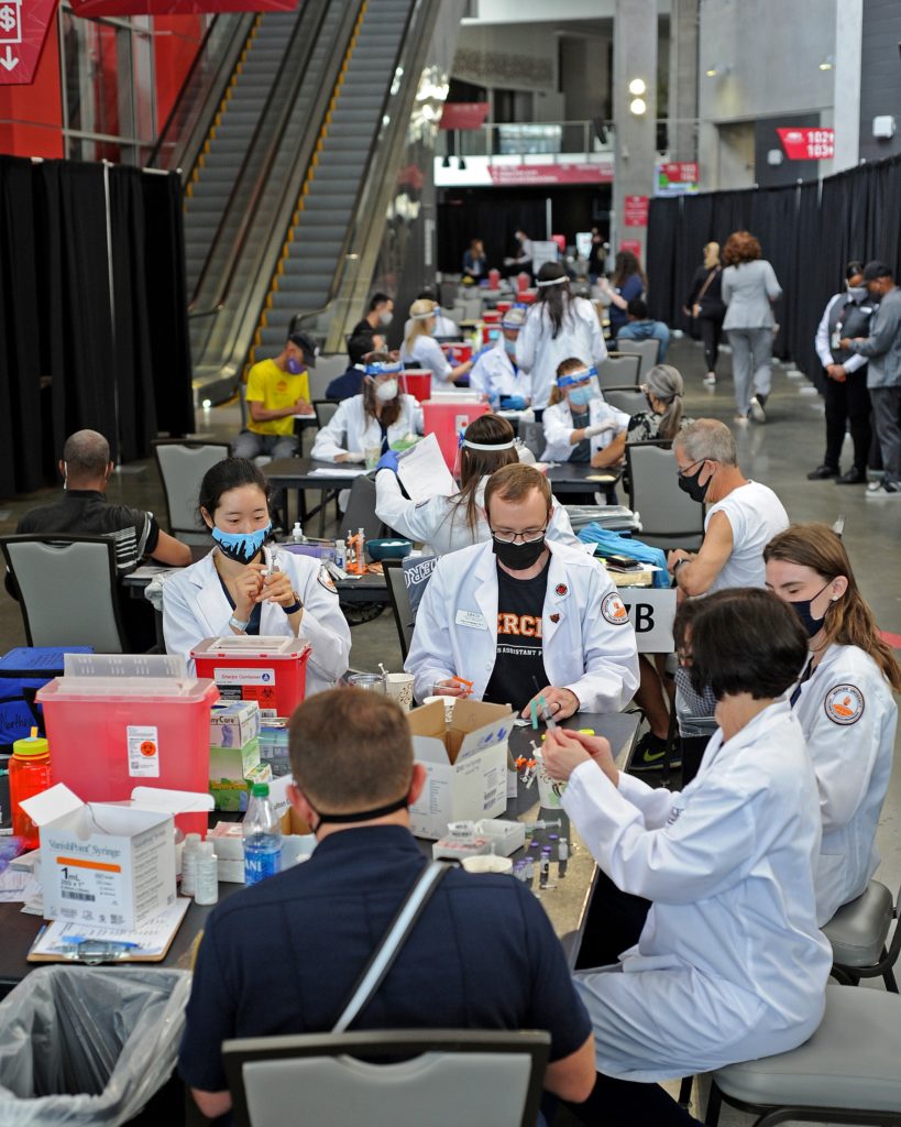 tables full of people wearing white lab coats
