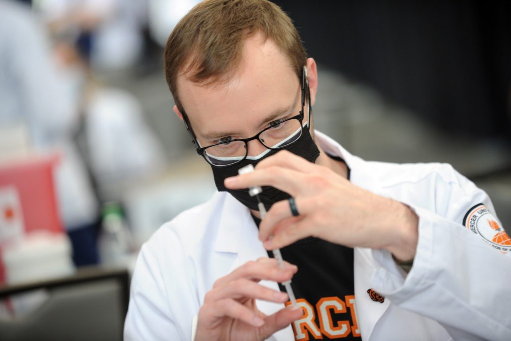 Tyler Fredlund, a second-year student in Mercer University's physician assistant program, draws a dose of the COVID-19 vaccine into a syringe.