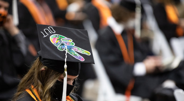 With graduation in sight, don’t lose steam now | Ask Kelly graduate wears a mortar board decorated with two fingers holding a peace sign and the word out