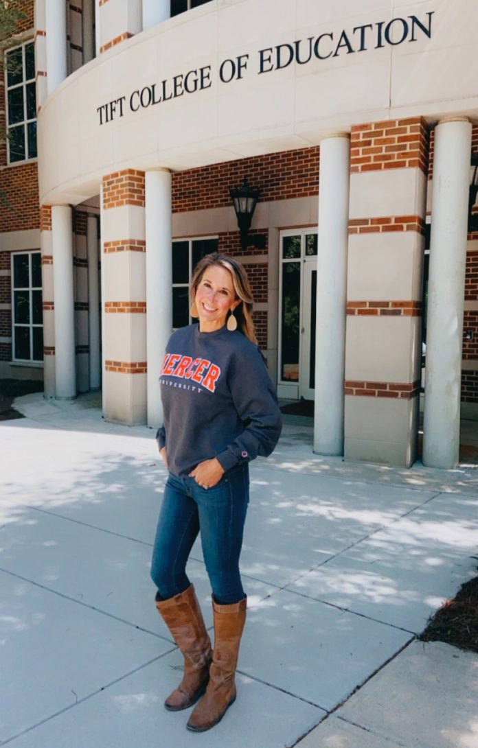 A woman in a mercer shirt stands in front of the tift college of education