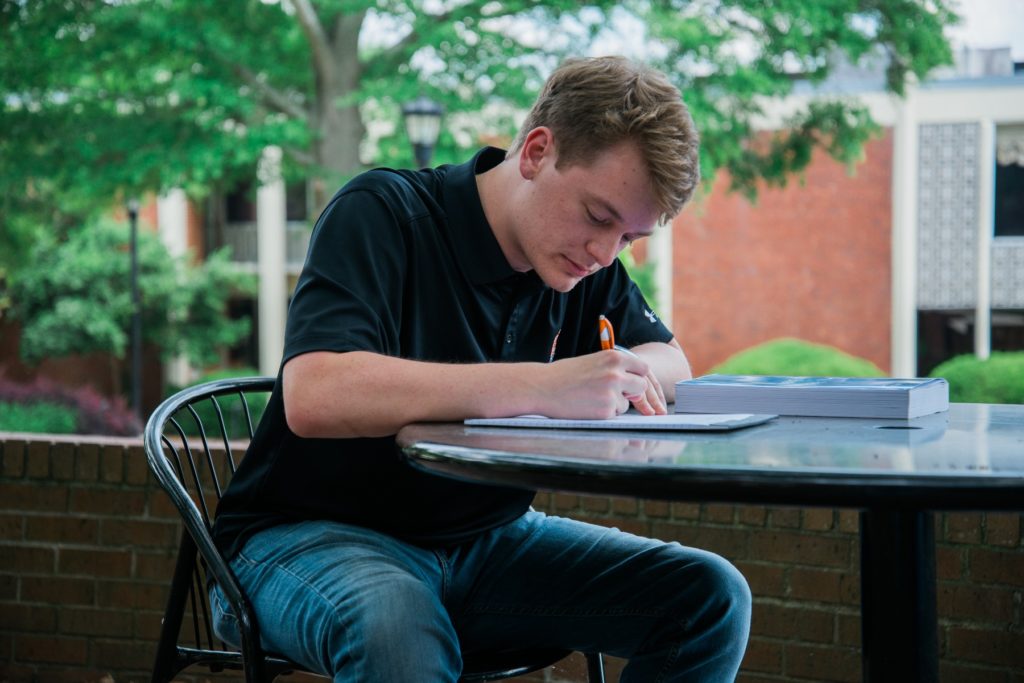 a college student sits at a table writing
