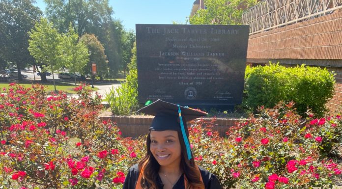 Graduate Spotlight: Chiquita Sanders A woman wearing a black graduation cap and gown and an orange stole sits on a bench