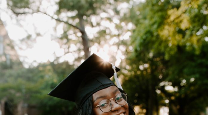Graduate Spotlight: Nadia Pressley A woman wearing a white dress and a graduation cap looks over her shoulder and smiles