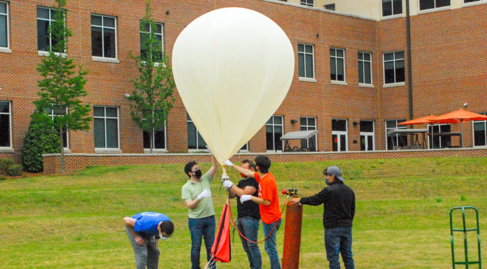 Balloon launch brings Mercer closer to offering low-cost experimentation near space Students gather around a giant balloon in a grassy field