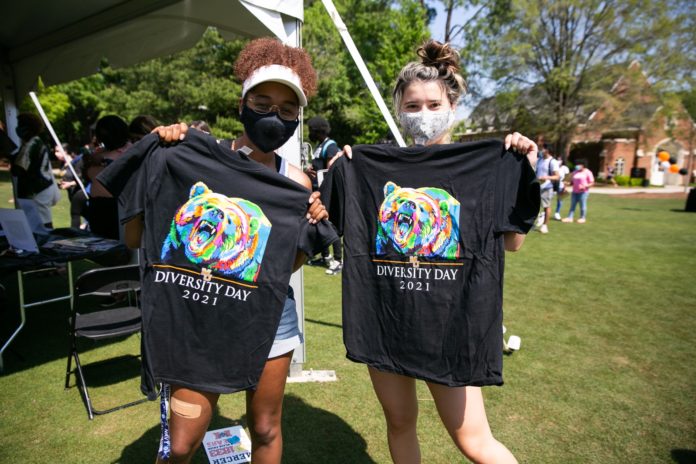 Two Mercer University students hold up black Diversity Day T-shirts
