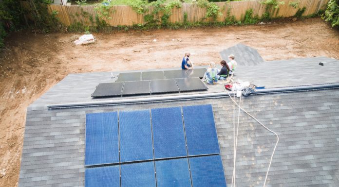 Engineering students help Habitat for Humanity homeowners save money and energy Aerial view of student installing solar panels on a roof