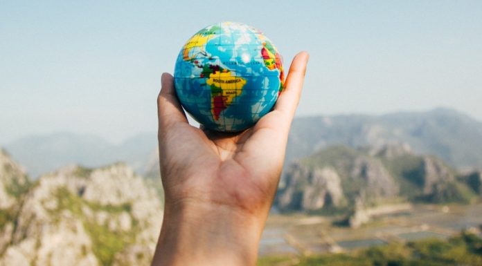 Tell professors about upcoming travel sooner rather than later | Ask Kelly a hand holds a globe in front of mountains