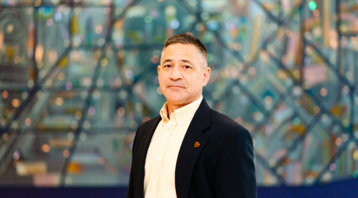 Michael Junod is grateful for the opportunity to work with students | Worker Bears Michael Junod stands in front of a glass mural.