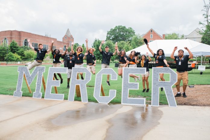 students jump behind letters that spell mercer