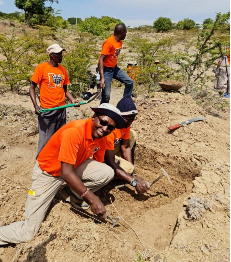 three men wearing orange shirt at an archaeological dig