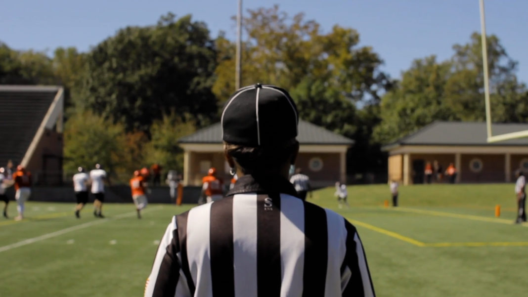 the back of a referee who is afacing a football field