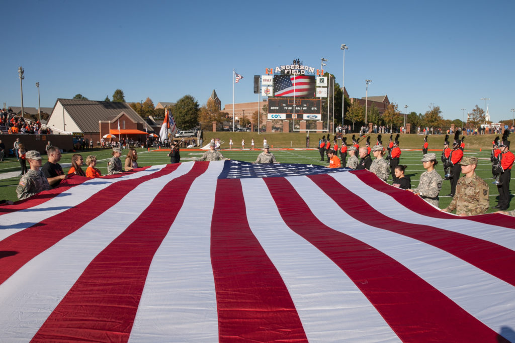 People hold a giant American flag across a football field