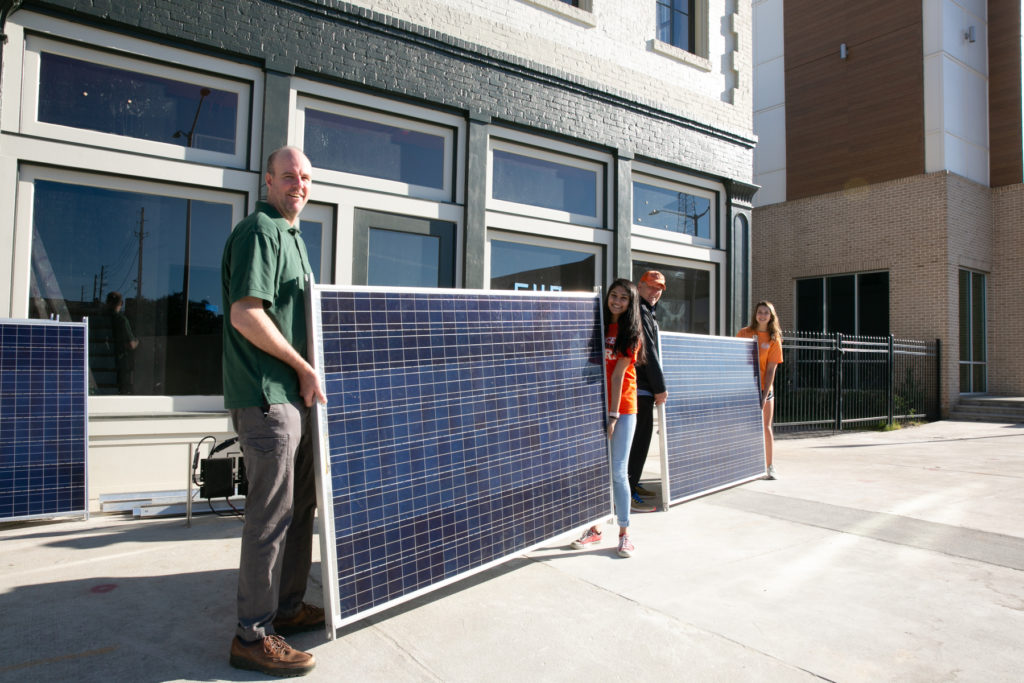 Four people hold two solar panels