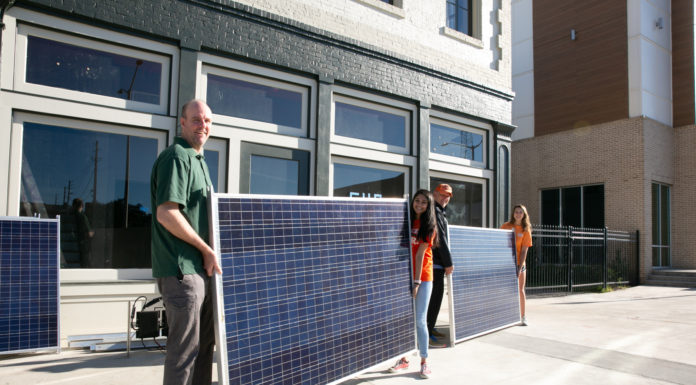 Professor remembered for innovative service to students, developing communities Four people hold two solar panels