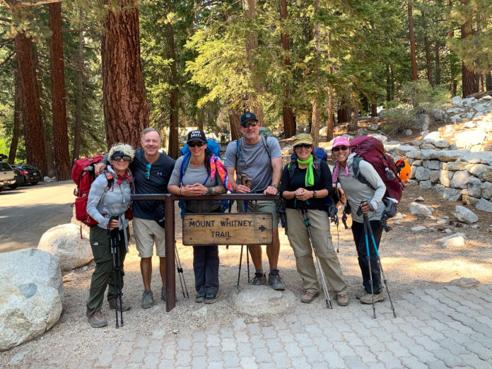 A group of six people pose for a picture at the Mount Whitney Trail sign