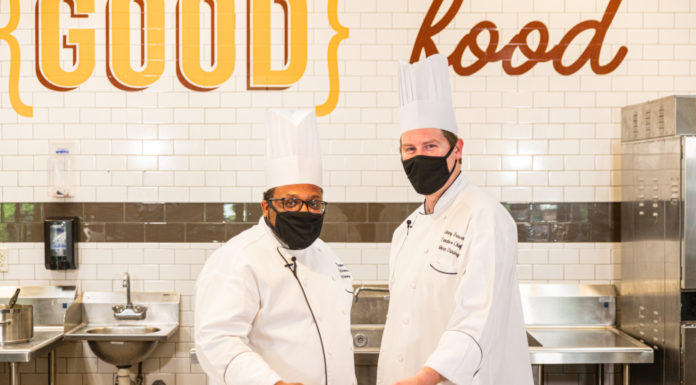 A ‘Cooking in the Cave’ spin on a Southern staple two chefs hold a plate of shrimp and grits