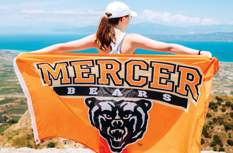 college student holds out mercer flag