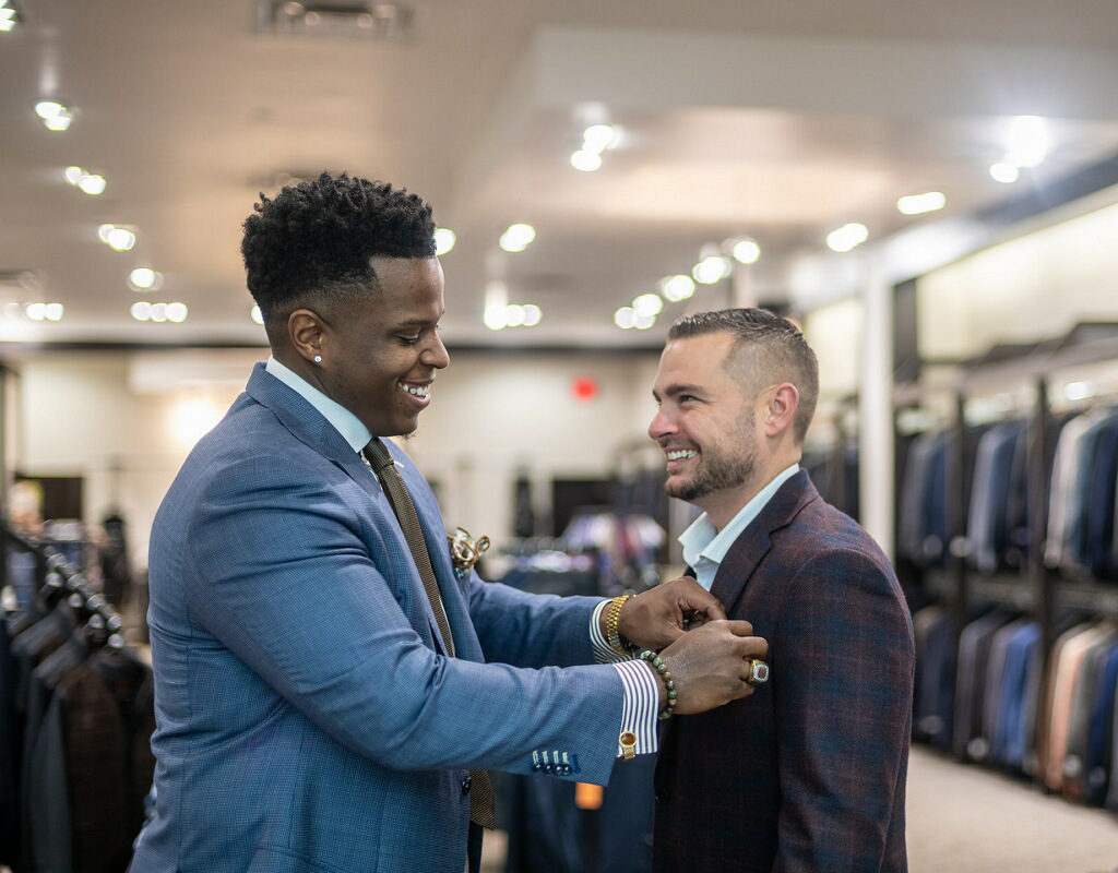 Kristian Smith, owner of P-Squared, adjusts the pocket square of man's suit.